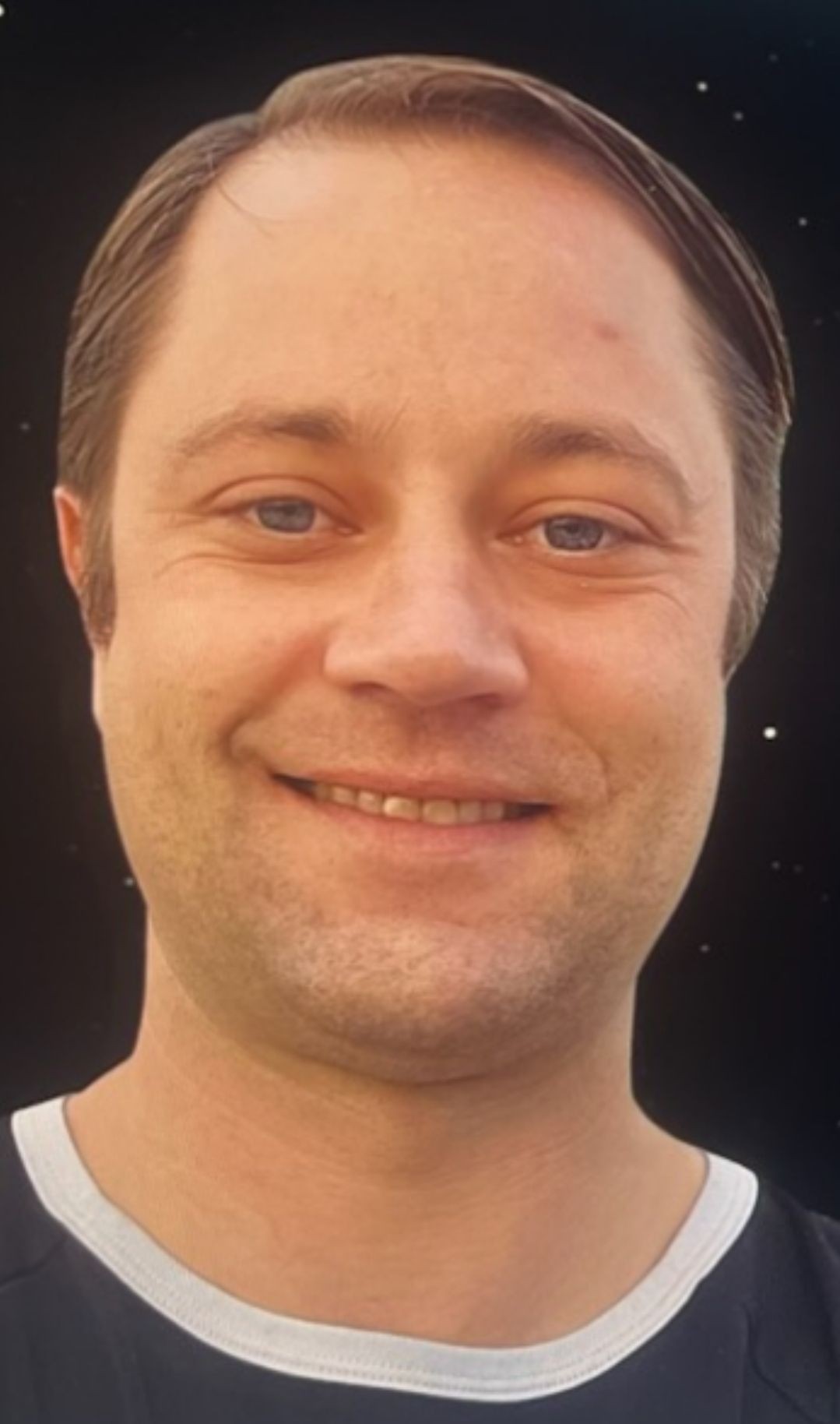 Close-up of a smiling person against a dark background.